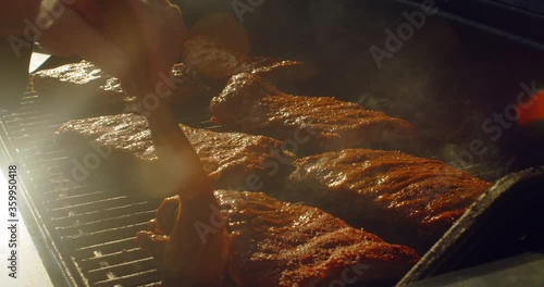 Juicy rack of ribs being basted and cooking on a bbq grill on a summer afternoon