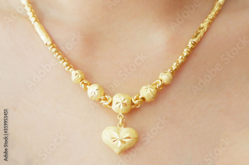 close up of Gold necklace with big gold heart pendant on neck of woman Which is a beautiful and expensive jewelry