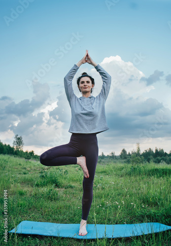 A young woman does yoga in nature. Sunny evening  good weather.