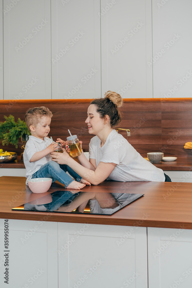 Fototapeta premium pregnant mother and son in the kitchen drink tea together 