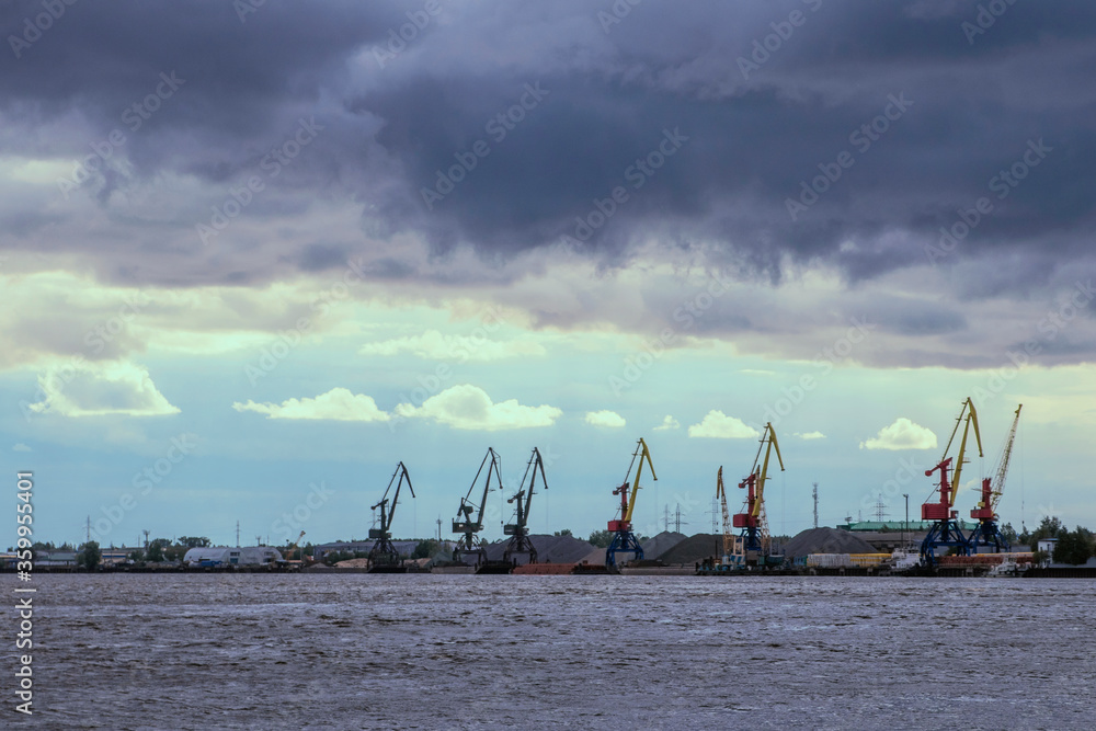 River port, port cranes. Water landscape. Cumulus clouds in cloudy weather.