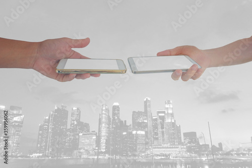 hand of two Asian people are hold smartphone close to each other for Technology knowledge exchange in the help of urban development.