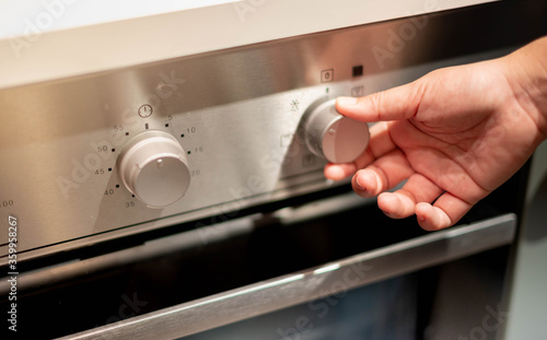 Close up female hand Opening Or Closing modern electric oven prepare to cooking  in the modern kitchen.