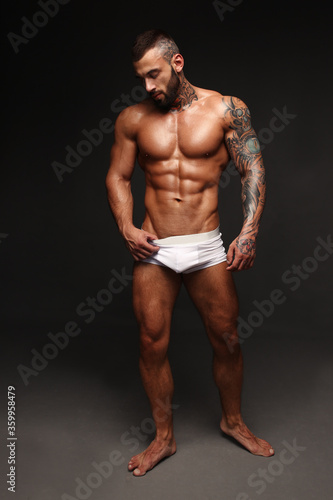 Sexy closeup portrait of handsome topless male model with beautiful eyes. Sexy man or muscular macho, bodybuilder, with muscle torso, body with six packs and abs poses on black background