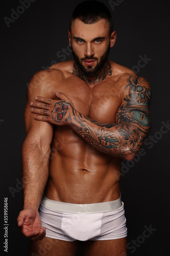Sexy closeup portrait of handsome topless male model with beautiful eyes. Sexy man or muscular macho, bodybuilder, with muscle torso, body with six packs and abs poses on in white panties