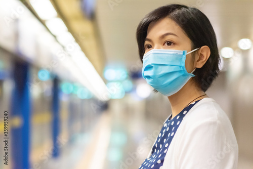 Asian Woman in face mask waiting metro for traveling to work