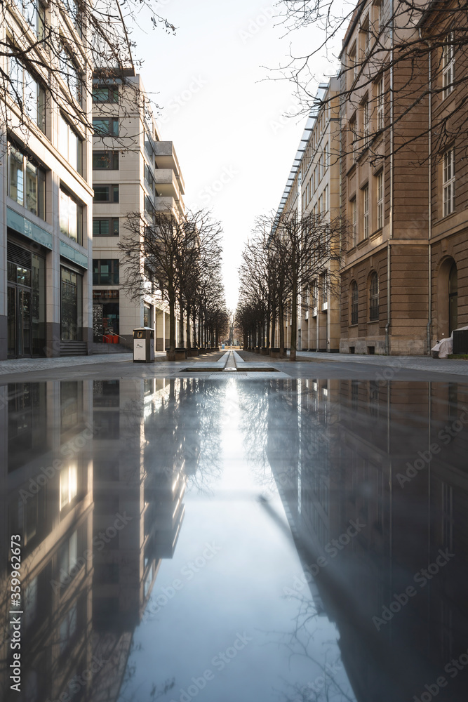 Germany, Berlin, Buildings reflecting on surface of wet empty street during COVID-19 epidemic Germany, Berlin, Buildings reflecting on surface of wet empty street during COVID-19 epidemic