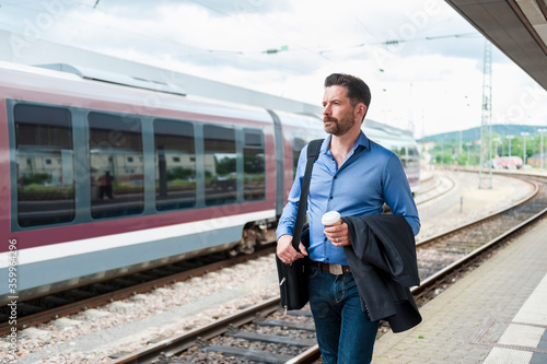 Wallpaper Mural Confident commuter walking on railroad station platform with coffee and blazer Torontodigital.ca