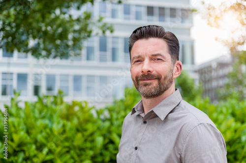 Portrait of smiling handsome bearded businessman in financial district photo