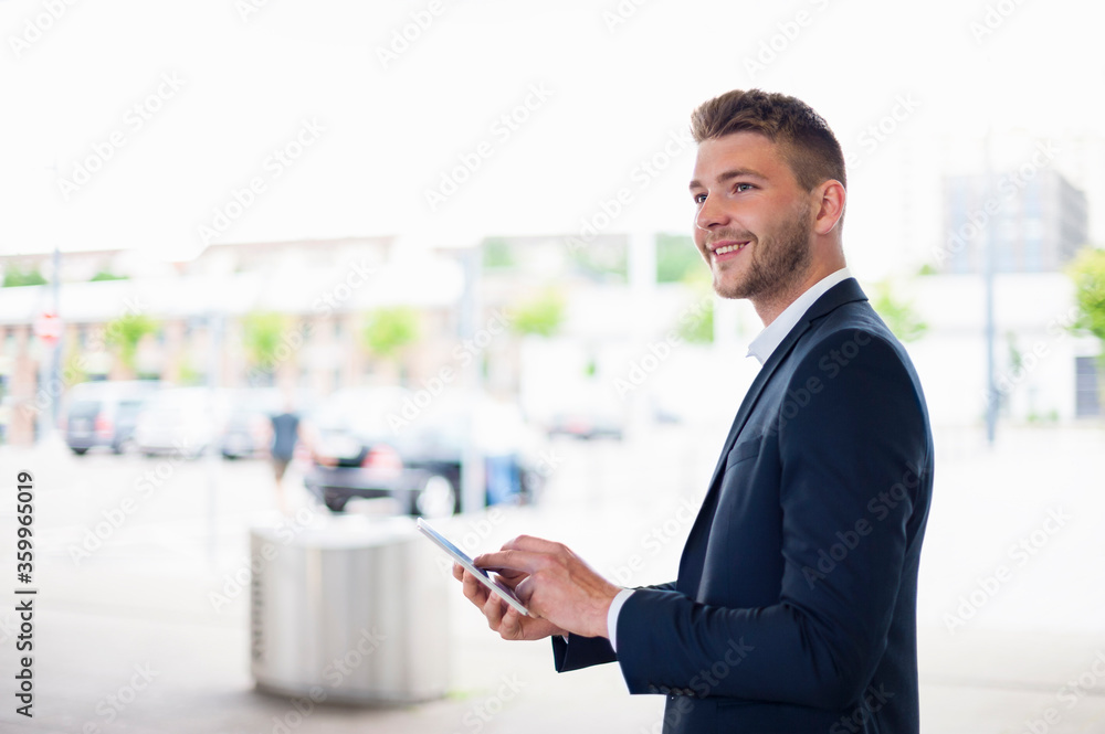 Smiling young businessman using tablet in the city Smiling young businessman using tablet in the city