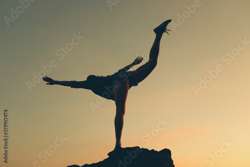 Woman standing on one leg at beach during sunset photo