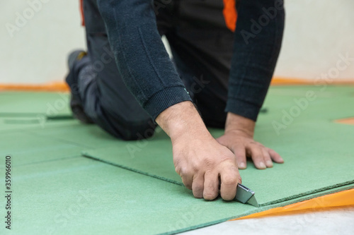Worker cutting underlayment for flooring photo