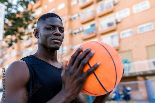 Portrait of basketball player holding basketball on basketball court photo