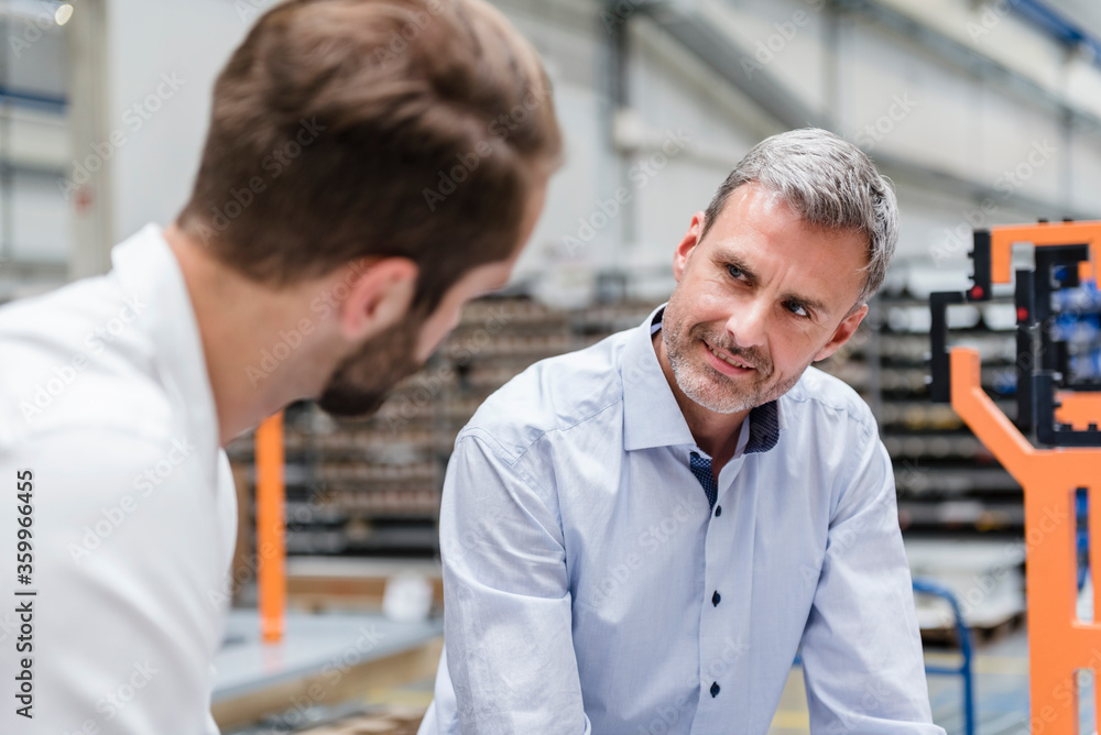 Portrait of mature man looking at colleague on factory shop floor Portrait of mature man looking at colleague on factory shop floor