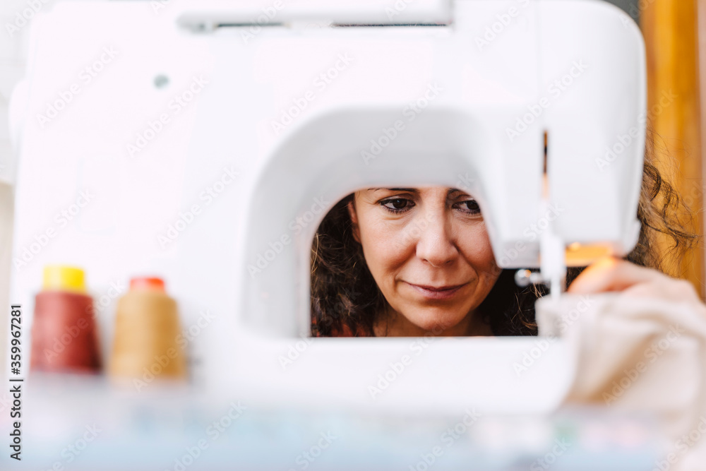 Close-up of focused woman sewing at home Close-up of focused woman sewing at home
