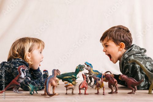 Brother and his little sister playing with toy dinosaurs photo