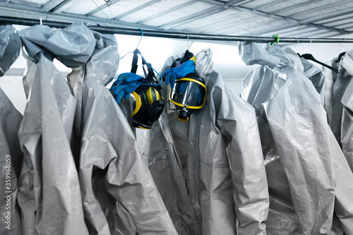 Protective suits and masks hanging from rack in locker room