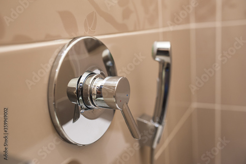 Hygienic shower with tap on the tiled wall in the toilet. Intimate hygiene. Close-up