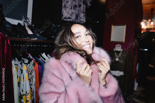 Portrait of smiling woman wearing pink fur jacket at thrift store photo