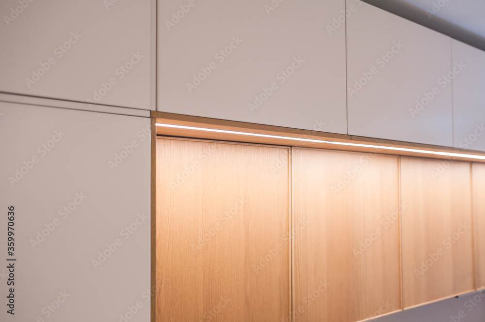 Fototapeta premium Kitchen cabinets, shelves with lighting, doors oak veneer and white. Close-up.