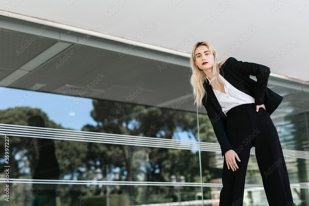 Portrait of young businesswoman wearing black pantsuit standing in front of an office building Portrait of young businesswoman wearing black pantsuit standing in front of an office building