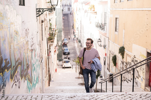 Young man walking up stairs in the city, Lisbon, Portugal