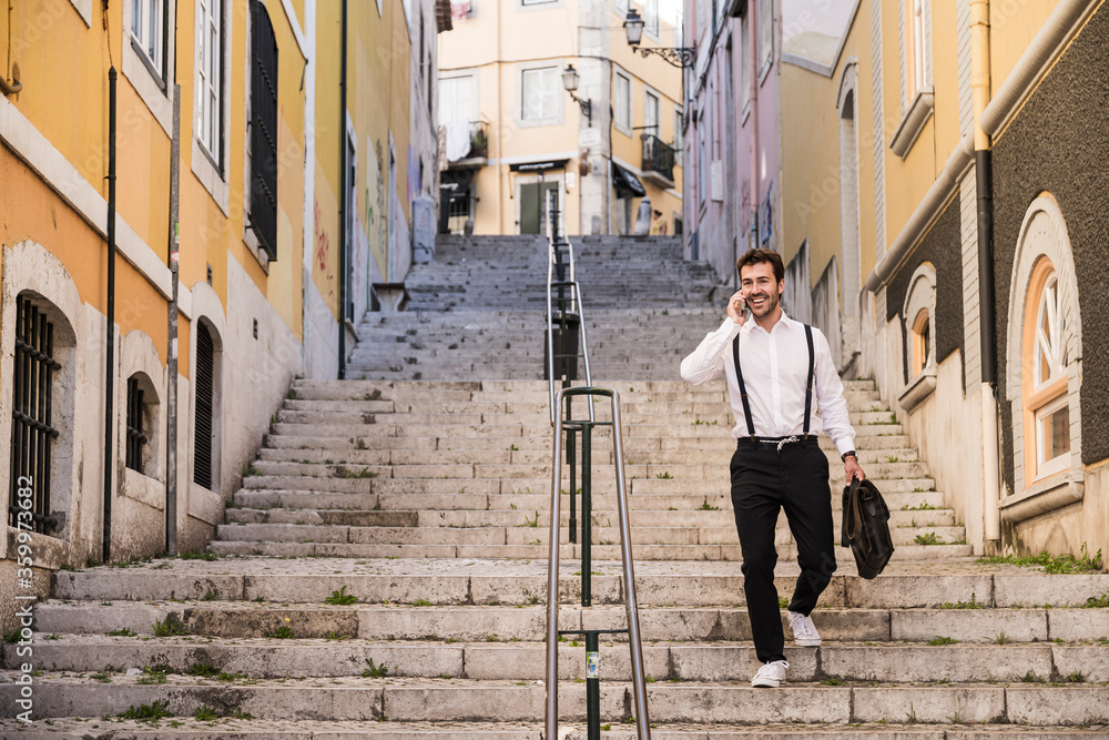 Smiling young man on the phone walking down stairs in the old town, Lisbon, Portugal Smiling young man on the phone walking down stairs in the old town, Lisbon, Portugal
