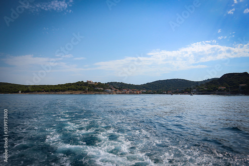 Sailing out of Vrgada island bay to the open, dalmatian sea, leaving island with beaches created by landslide and with no car traffic behind