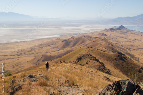 View from Frary Peak on Antelope Island, Great Salt Lake, looking south on the spine of the island. Lonely girl hiking on trail with gold grass on sunny day