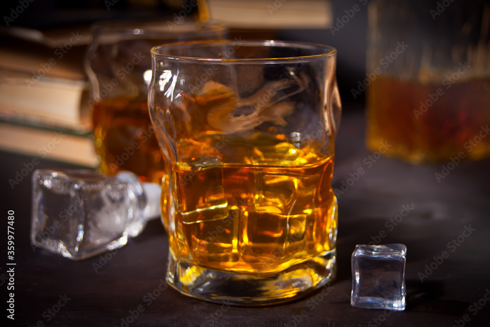 whiskey with ice on a wooden table. Nearby old books. whiskey with ice on a wooden table. Nearby old books.