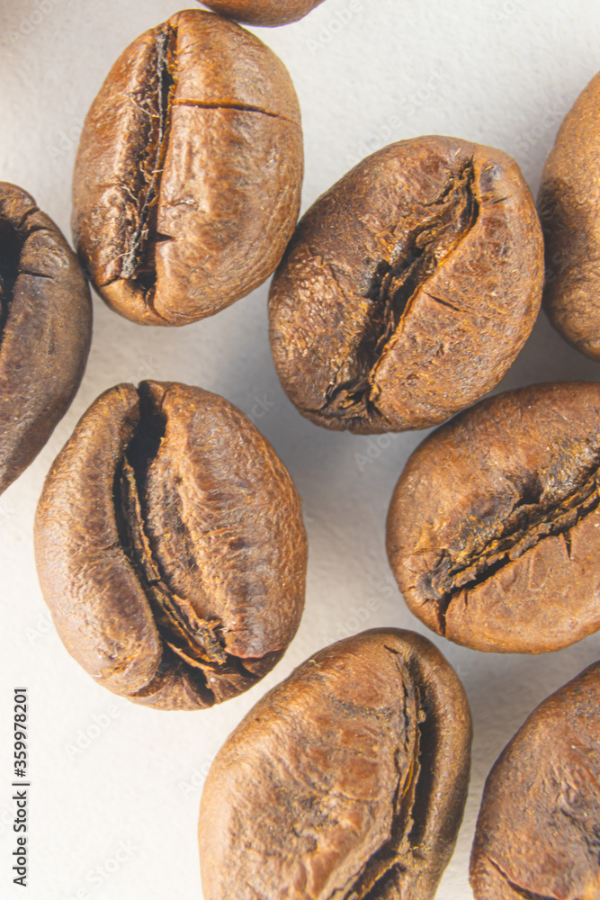 Brown coffee grains on a white paper background. Fragrant coffee grains close-up.