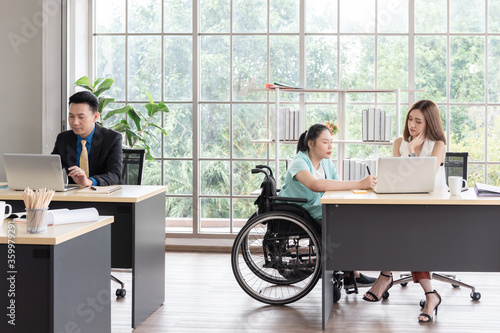 Asian disabled business woman woking together with her colleague at worplace