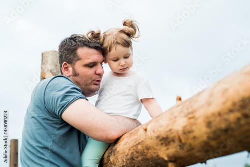 Father andbeautiful baby girl in the village. Sitting high on a wooden fence. Daughter hugs and kisses her father. tender happy family. father's day. photo