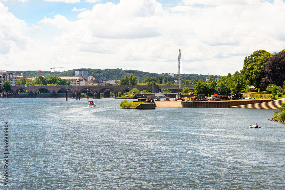The Moselle River in the city center in West Germany, visible old concrete bridge and port for launching water units.