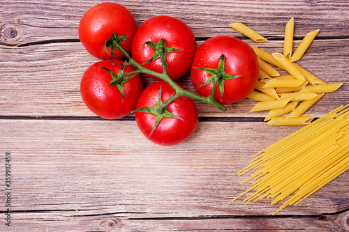 Bunch of raw spaghetti with a truss of tomatoes in a rustic scene