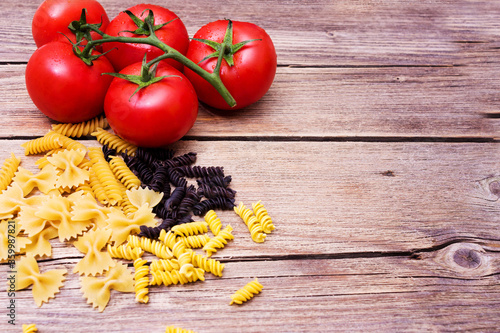 Bunch of raw spaghetti with a truss of tomatoes in a rustic scene