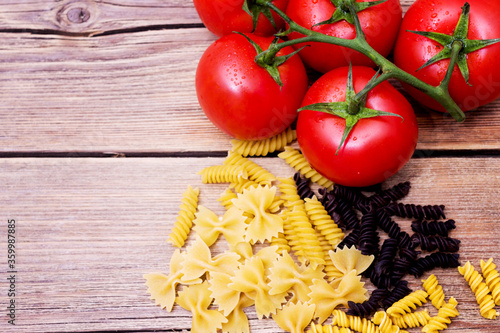 Bunch of raw spaghetti with a truss of tomatoes in a rustic scene