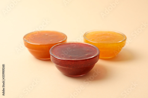 Bowls with jam on beige background, space for text
