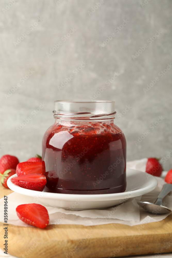 Composition with strawberry jam on wooden table against gray background Composition with strawberry jam on wooden table against gray background