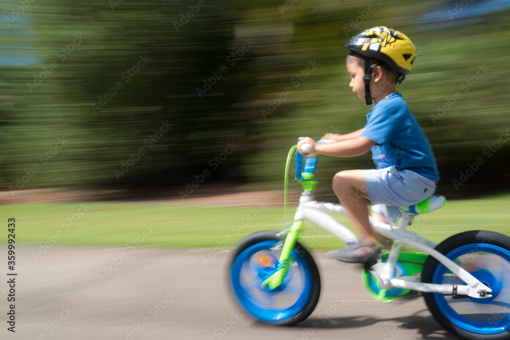 4 year old mixed race boy learns to ride his new bike for the first time. With motion blur 4 year old mixed race boy learns to ride his new bike for the first time. With motion blur