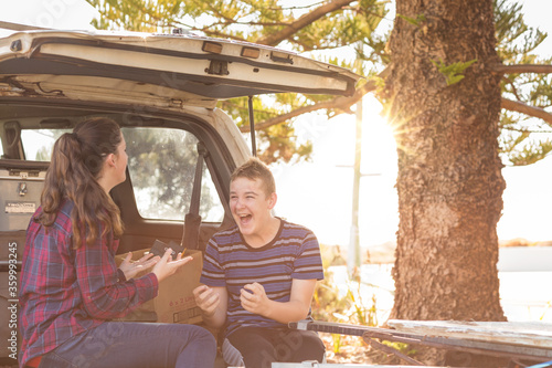 Young couple sitting on tailgate of 4WD vehicle photo