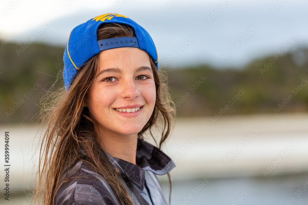 Girl with tousled brown hair wearing baseball cap backwards Stock Photo |  Adobe Stock