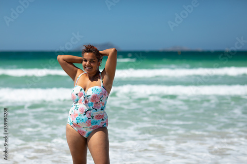 cheerful plus sized woman on beach in swimsuit