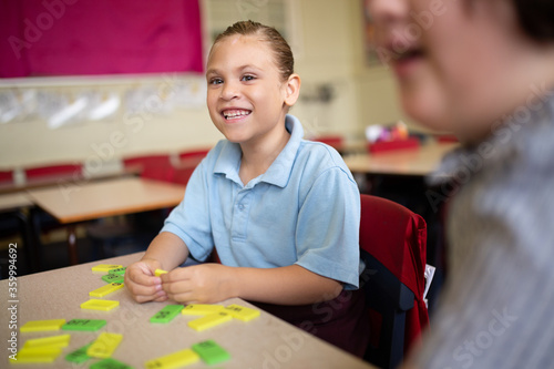 Indigenous primary school student smiling working with coloured word tiles