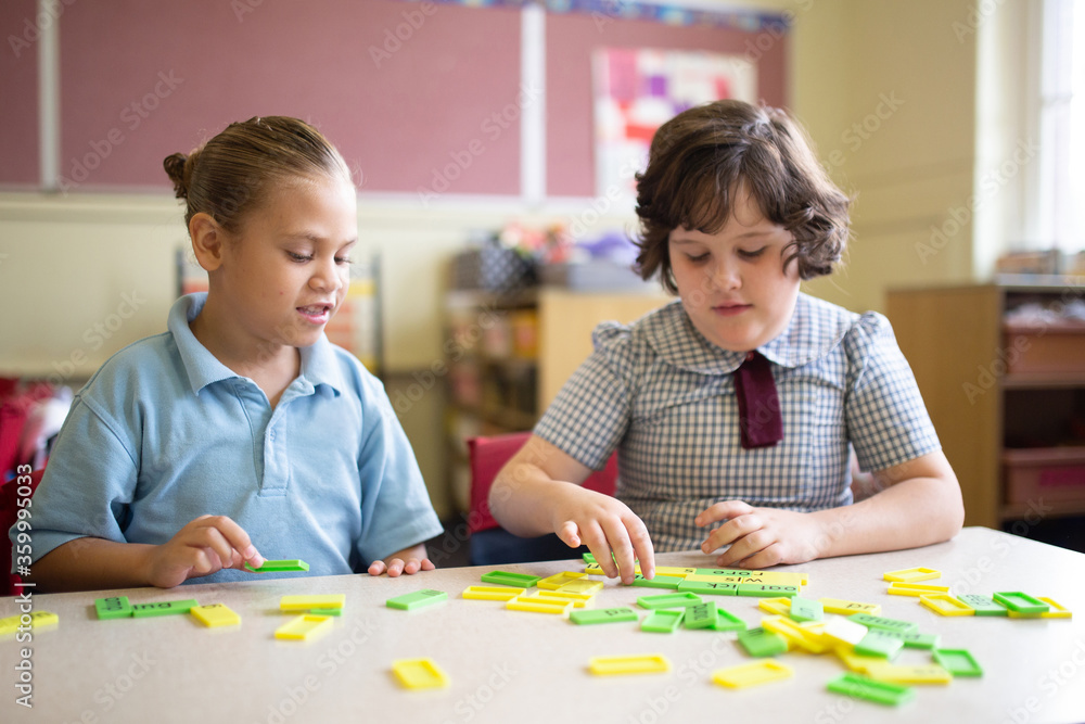 Two primary school girl students collaborating with coloured word tiles Two primary school girl students collaborating with coloured word tiles