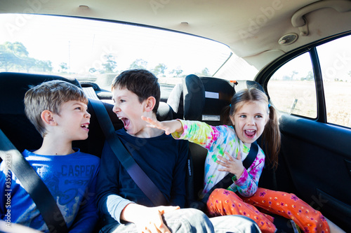 Three happy siblings in the back of a car photo