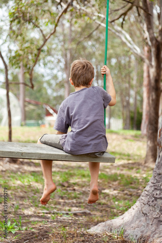 Young boy on big home made swing in backyard