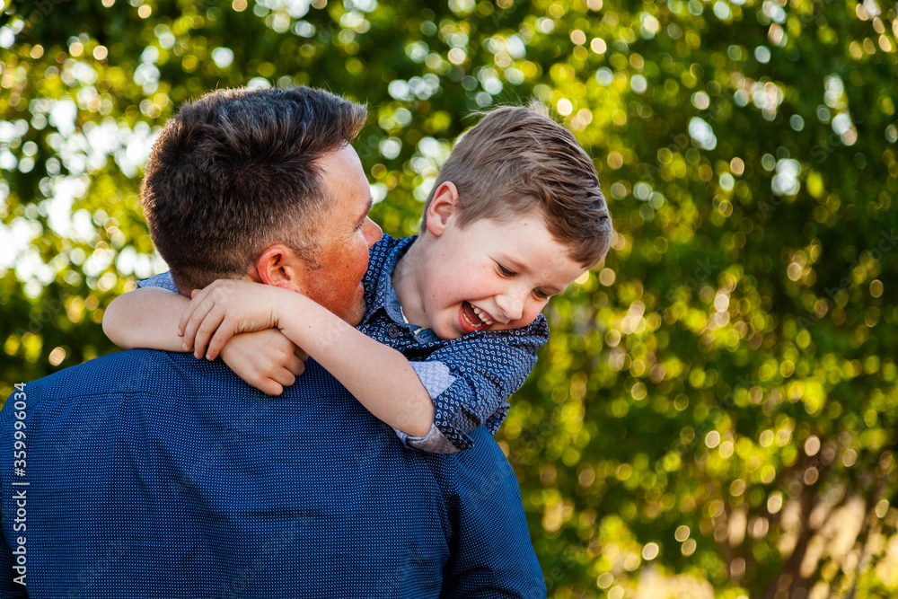 Father and young son laugh together and hug outside Father and young son laugh together and hug outside