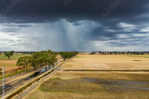 Aerial view of a storm cloud dropping rain on dry farmland photo