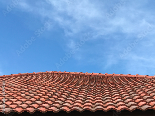 Red burgundy roof tiles on blue sky.